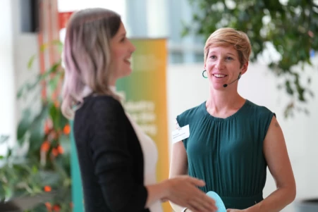 Two women discussing on stage during a conference about AI.